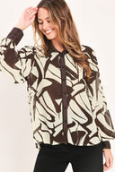 A woman wearing a long-sleeve button-up blouse with an abstract brown and cream pattern | Flying Tomato