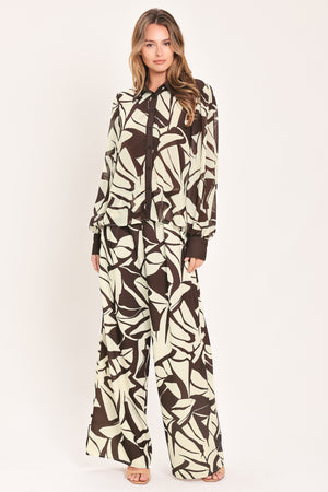 A woman wearing a long-sleeve button-up blouse with an abstract brown and cream pattern | Flying Tomato