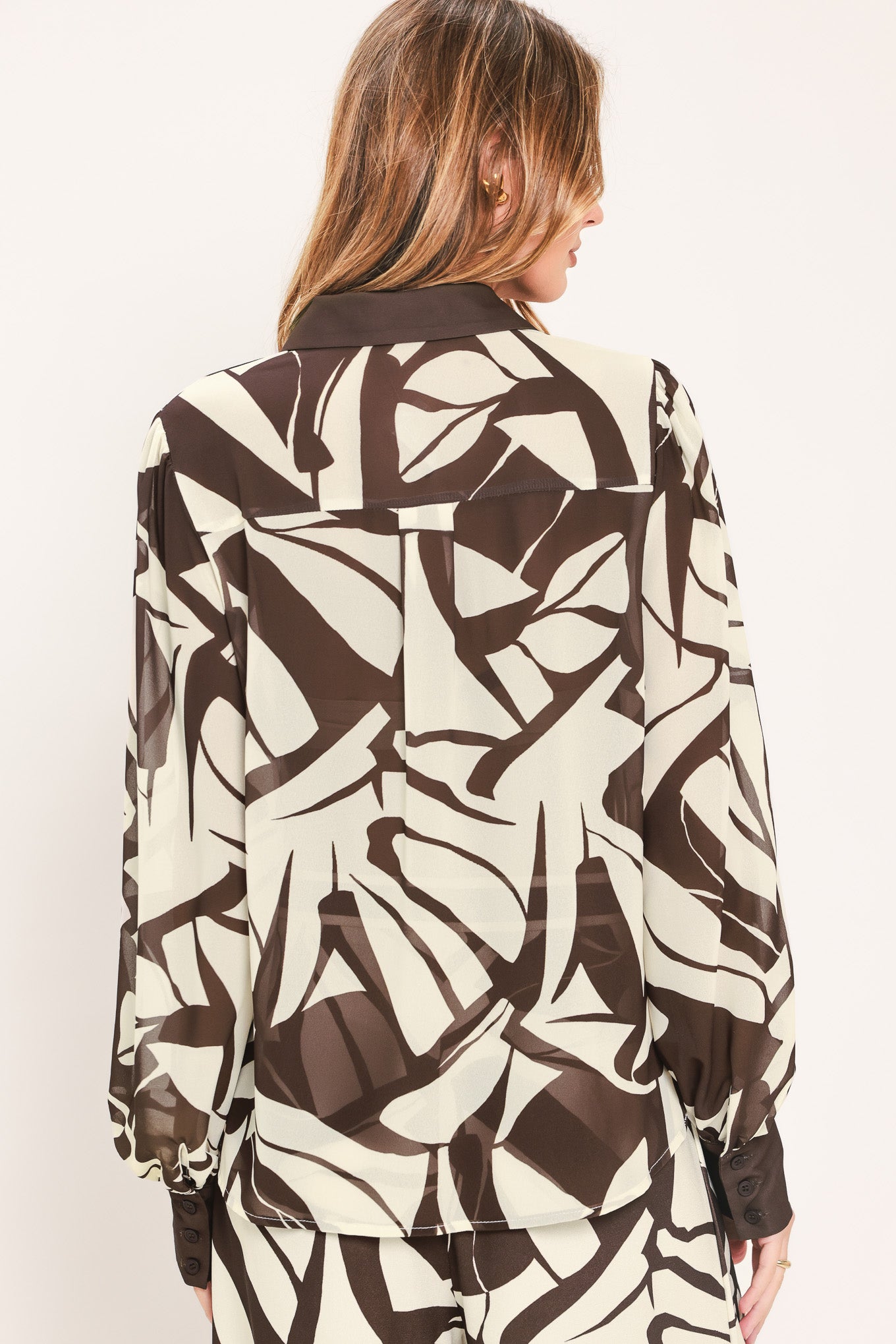 A woman wearing a long-sleeve button-up blouse with an abstract brown and cream pattern | Flying Tomato
