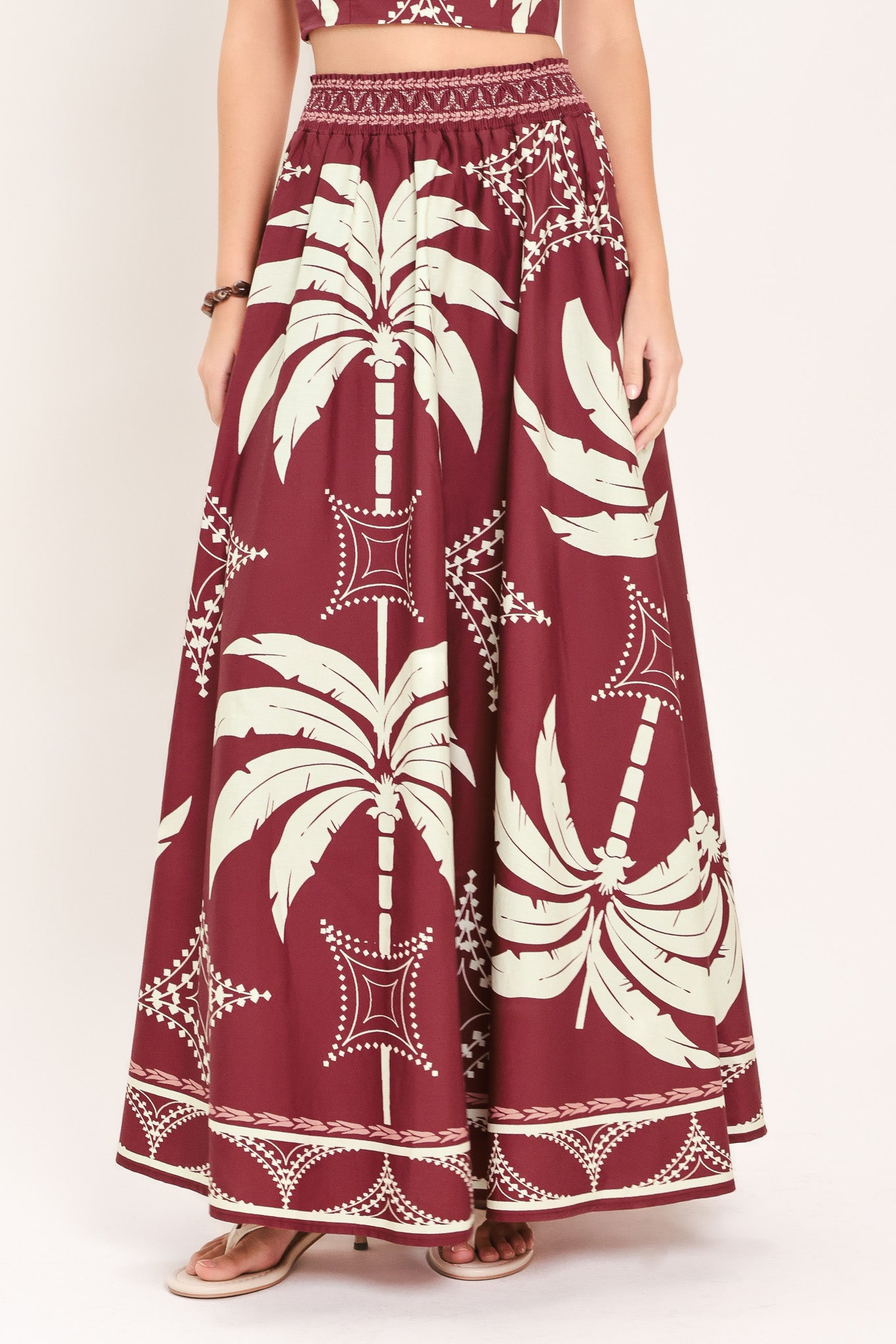 Woman wearing a red and white patterned top and skirt set with printed palm tree design | Flying Tomato
