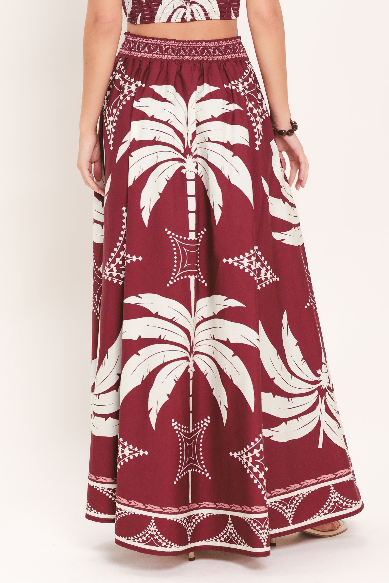 Woman wearing a red and white patterned top and skirt set with printed palm tree design | Flying Tomato