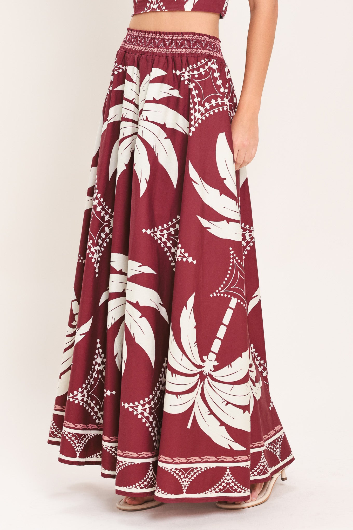 Woman wearing a red and white patterned top and skirt set with printed palm tree design | Flying Tomato