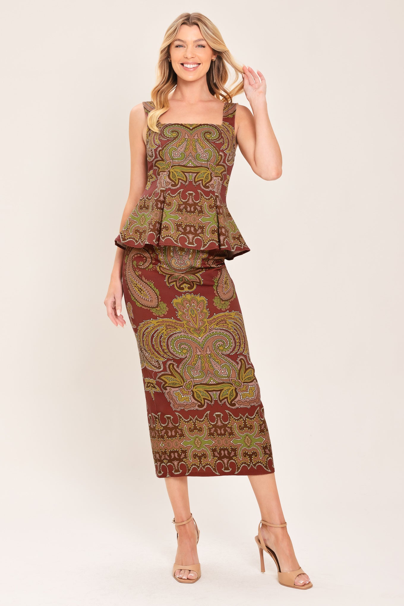 A woman wearing a sleeveless peplum top with a brown, olive green, and beige paisley pattern | Flying Tomato