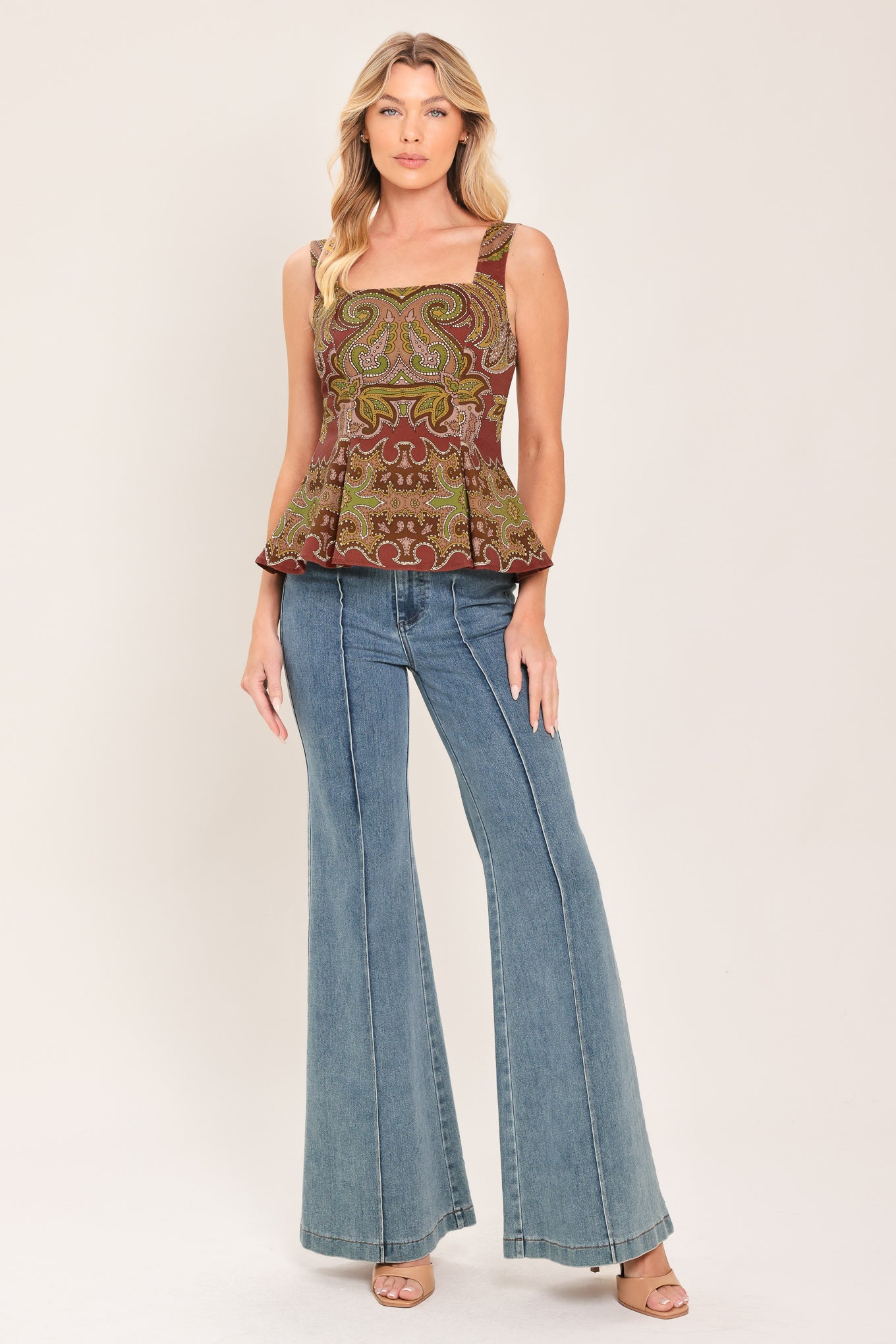 A woman wearing a sleeveless peplum top with a brown, olive green, and beige paisley pattern | Flying Tomato