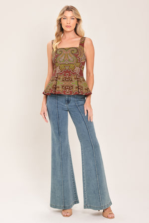 A woman wearing a sleeveless peplum top with a brown, olive green, and beige paisley pattern | Flying Tomato