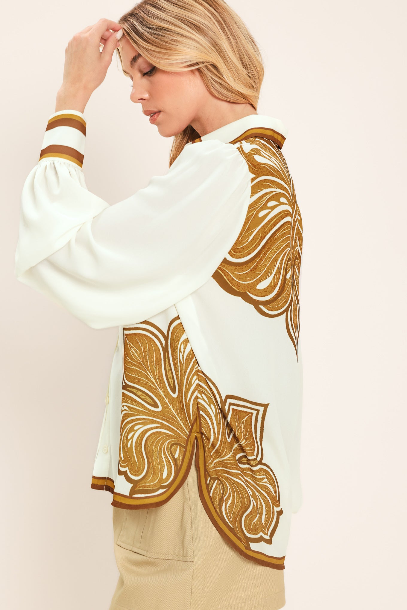 Woman wearing a white long sleeve  button down blouse with brown leaf-like print | Flying Tomato
