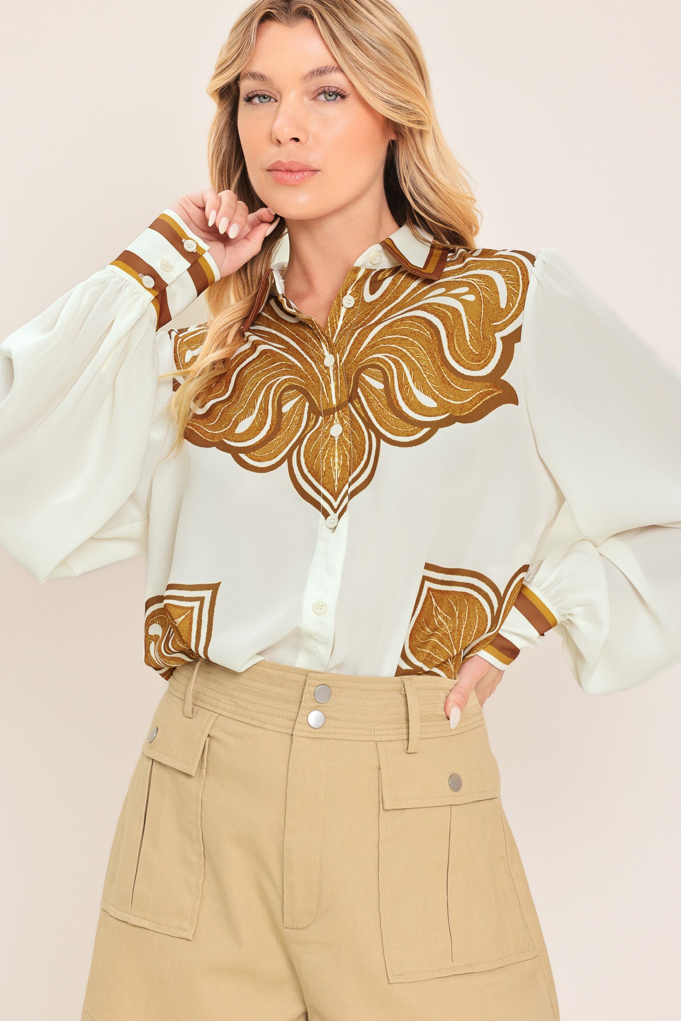 Woman wearing a white long sleeve  button down blouse with brown leaf-like print | Flying Tomato