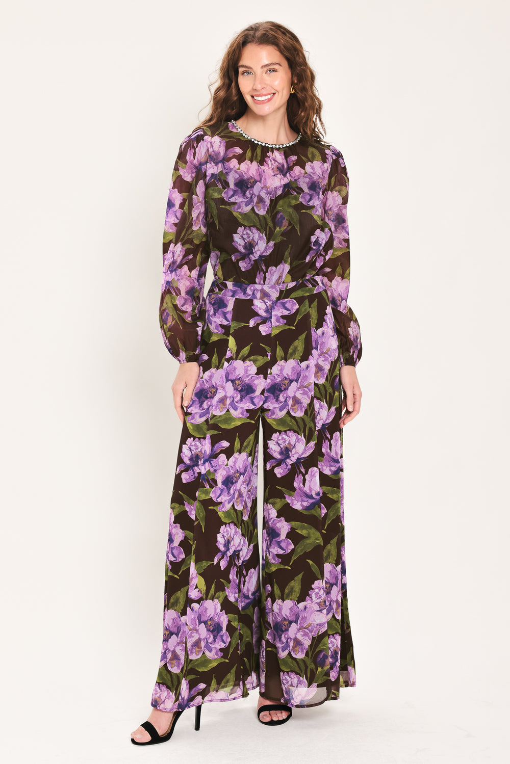 A woman wearing a dark brown sheer long-sleeve top with a vibrant purple and green floral print | Flying Tomato