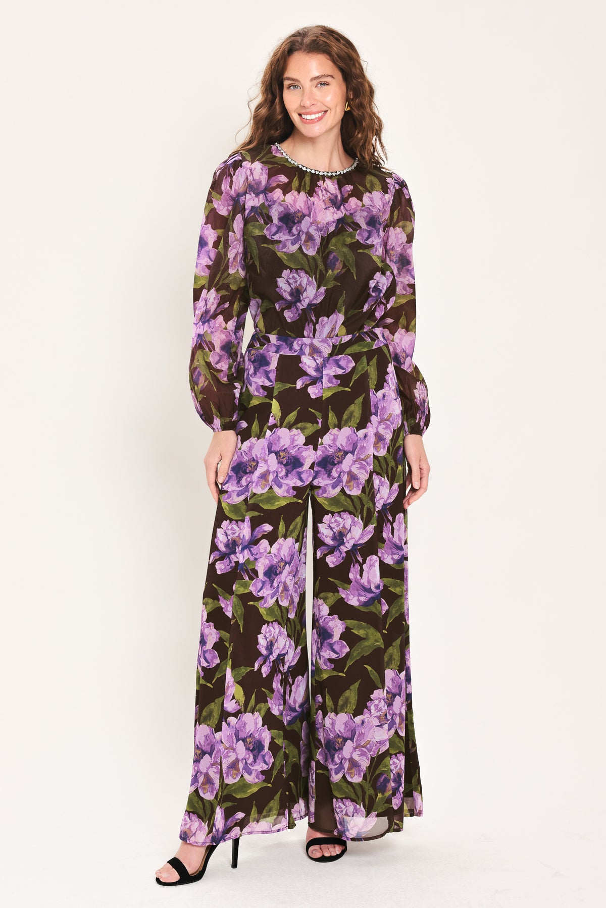 A woman wearing a dark brown sheer long-sleeve top with a vibrant purple and green floral print | Flying Tomato