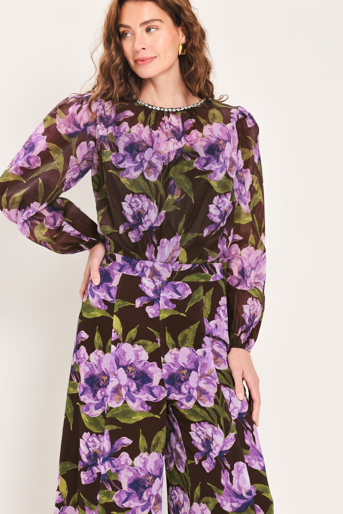 A woman wearing a dark brown sheer long-sleeve top with a vibrant purple and green floral print | Flying Tomato