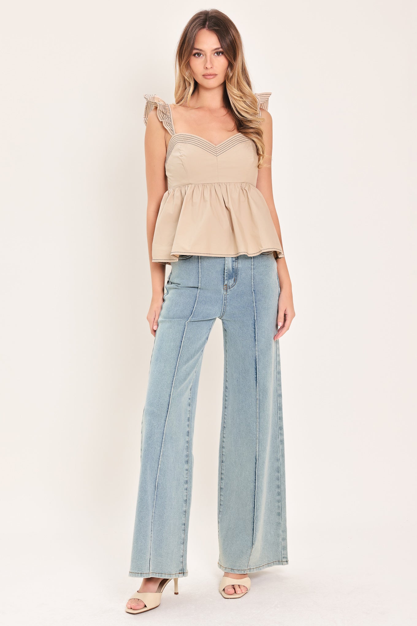 Woman wearing a beige top with ruffled sleeves featuring sweetheart neckline, peplum and smocked back bodice | Flying Tomato