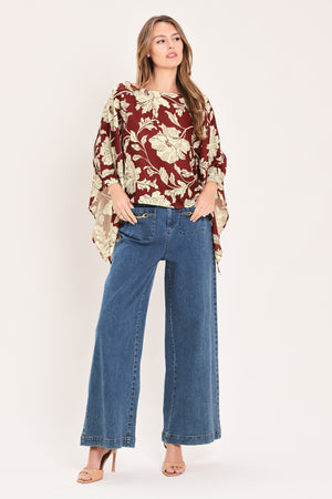 A woman wearing a burgundy and cream floral print top with wide bell sleeves | Flying Tomato