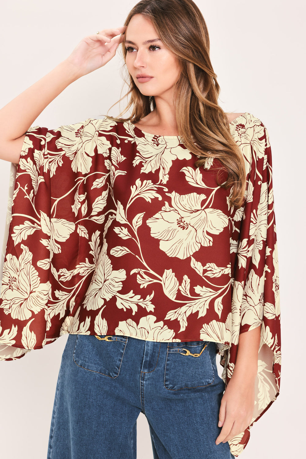 A woman wearing a burgundy and cream floral print top with wide bell sleeves | Flying Tomato