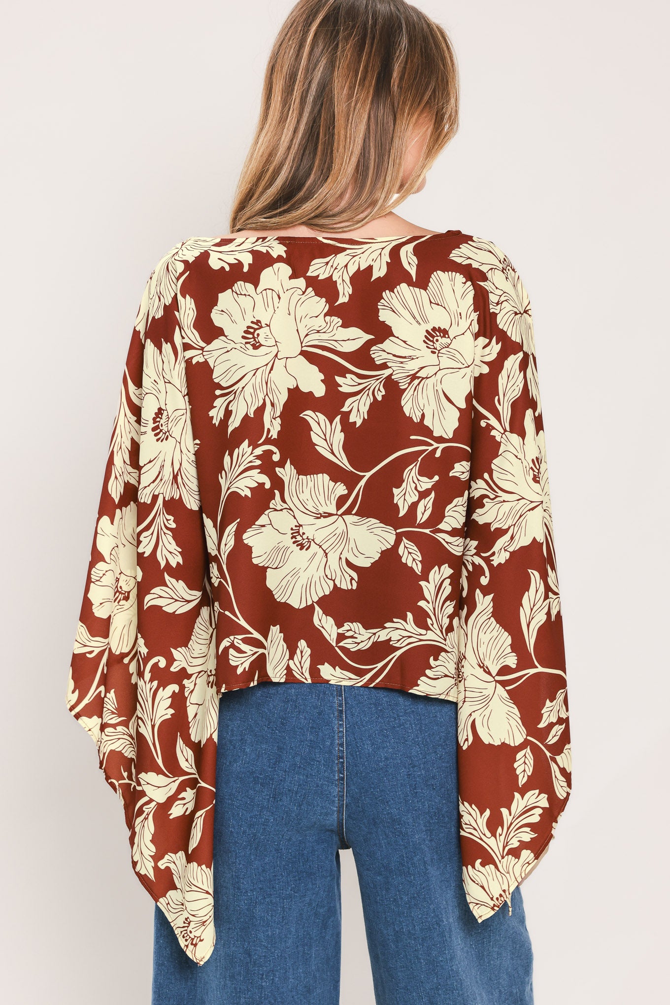 A woman wearing a burgundy and cream floral print top with wide bell sleeves | Flying Tomato