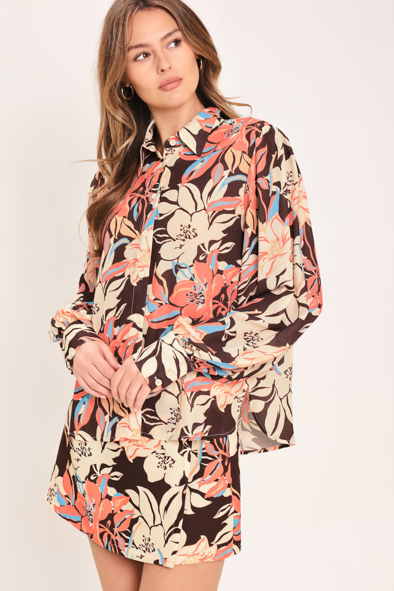 Woman wearing a long sleeve dark brown woven top with floral print featuring collar and button down | Flying Tomato