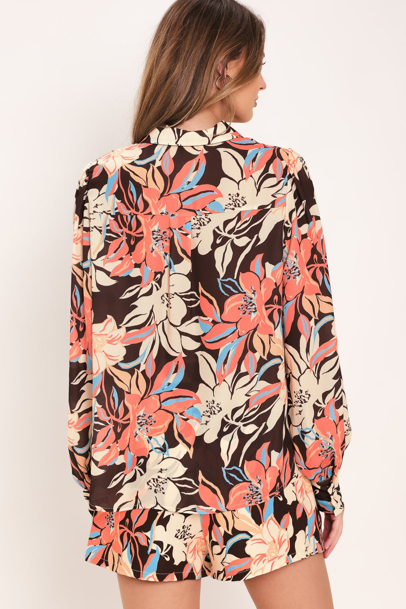 Woman wearing a long sleeve dark brown woven top with floral print featuring collar and button down | Flying Tomato