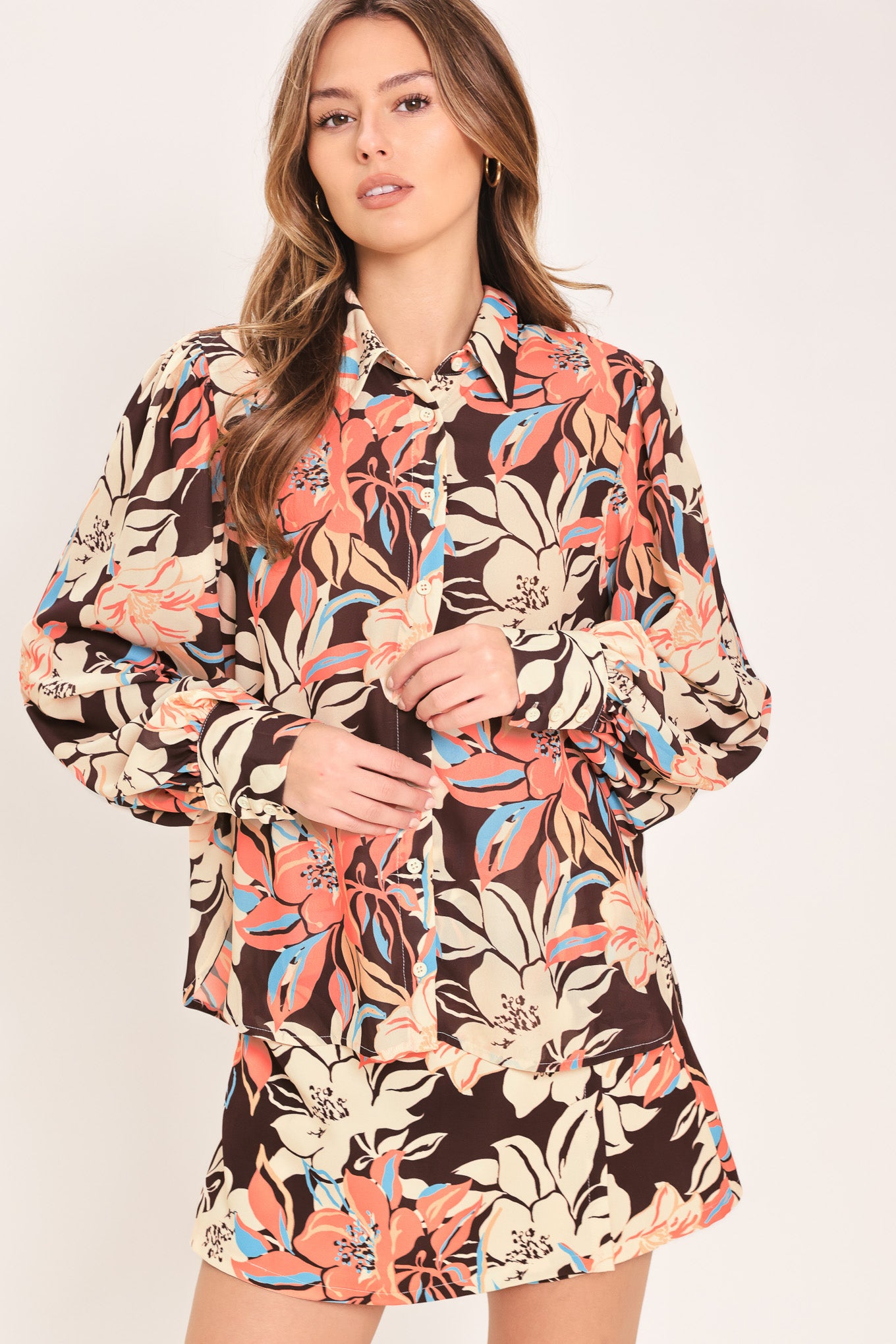 Woman wearing a long sleeve dark brown woven top with floral print featuring collar and button down | Flying Tomato