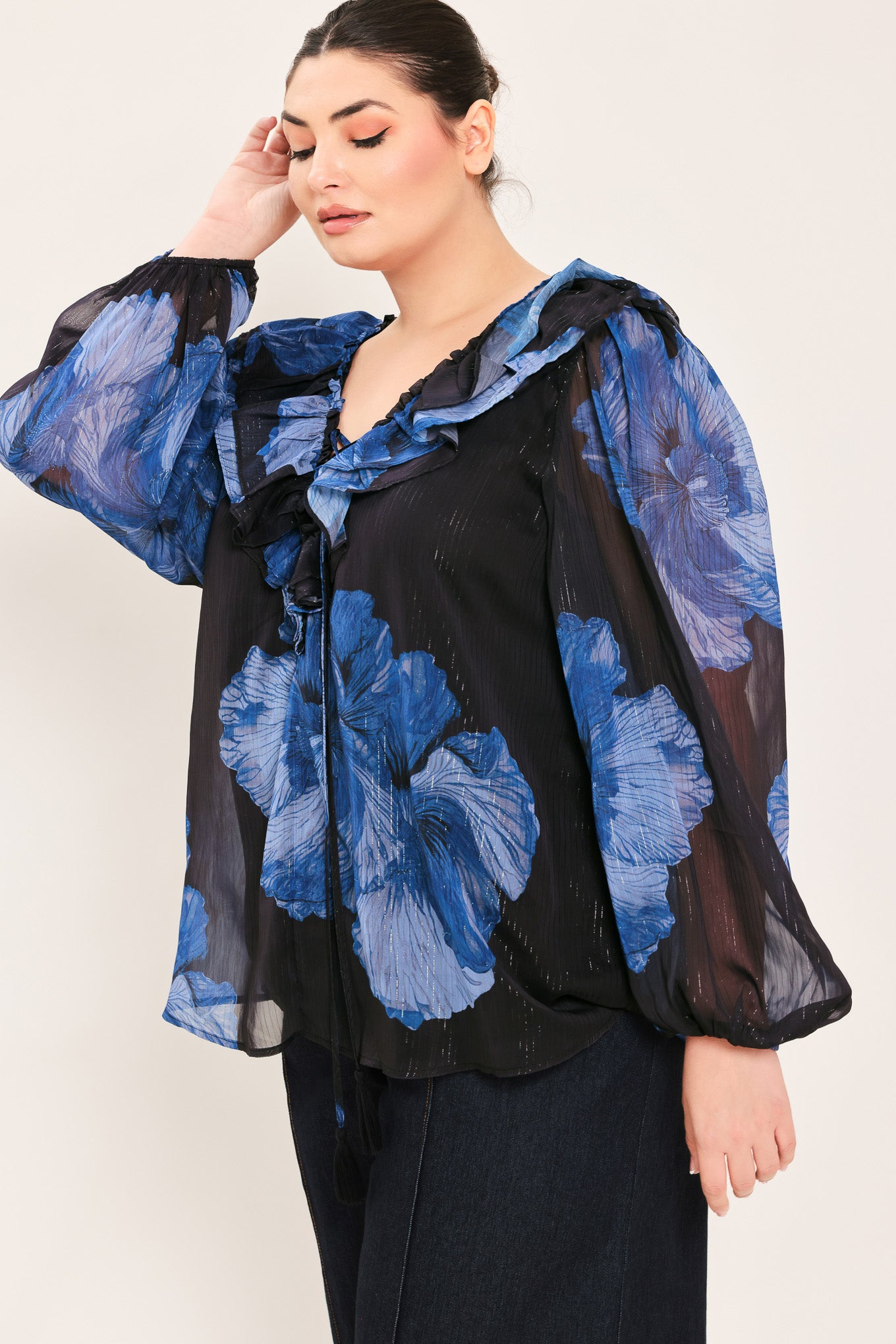 A woman wearing a black blouse with a blue floral print and ruffled collar details | Plus Curve Flying Tomato