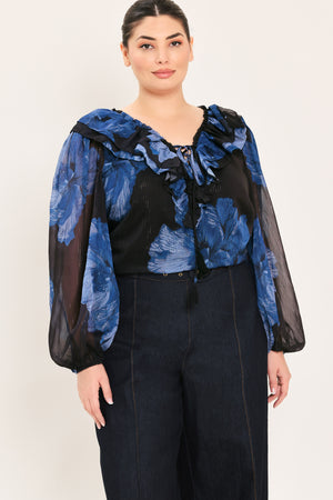 A woman wearing a black blouse with a blue floral print and ruffled collar details | Plus Curve Flying Tomato