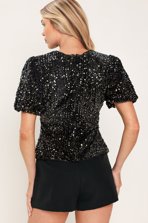A woman modeling a black sequined short-sleeve top with puffed sleeves | Flying Tomato