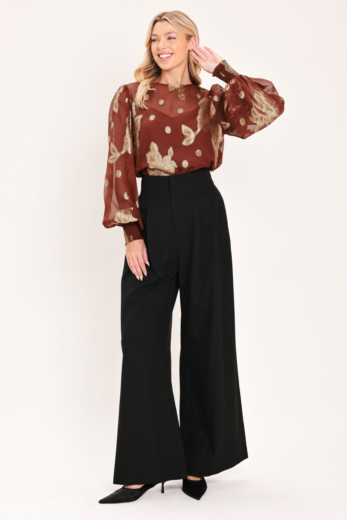 A woman wearing a sheer rust-brown/brick-colored blouse with metallic gold floral embroidery and puff sleeves | Flying Tomato