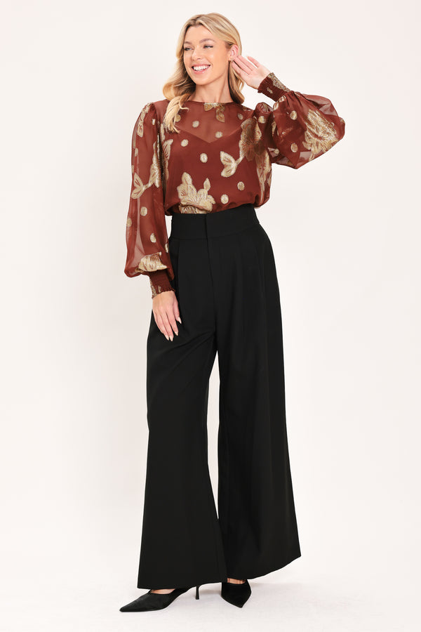A woman wearing a sheer rust-brown/brick-colored blouse with metallic gold floral embroidery and puff sleeves | Flying Tomato