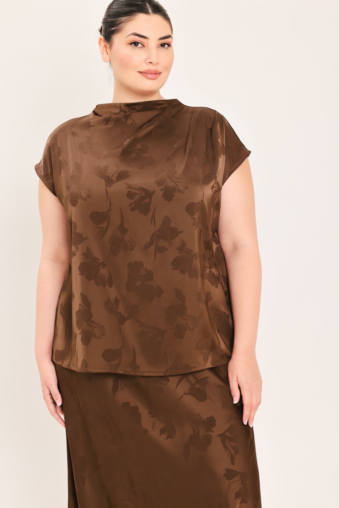 A woman modeling a brown short-sleeve top with a darker brown floral jacquard pattern, paired with a matching brown skirt | Plus Curve Flying Tomato