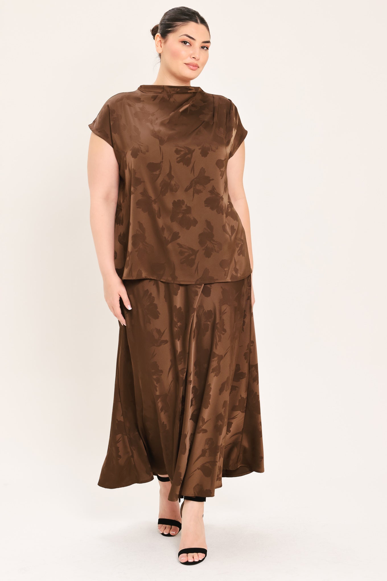 A woman modeling a brown short-sleeve top with a darker brown floral jacquard pattern, paired with a matching brown skirt | Plus Curve Flying Tomato