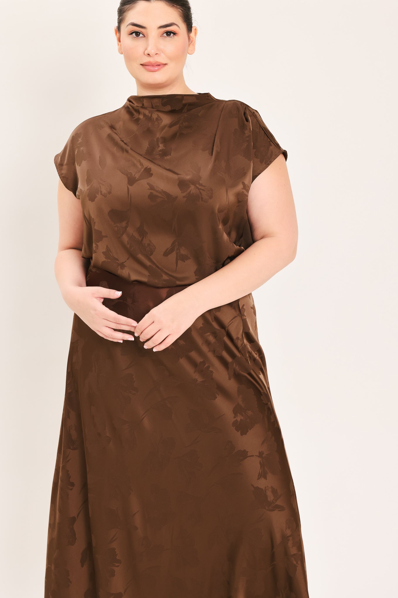 A woman modeling a brown short-sleeve top with a darker brown floral jacquard pattern, paired with a matching brown skirt | Plus Curve Flying Tomato