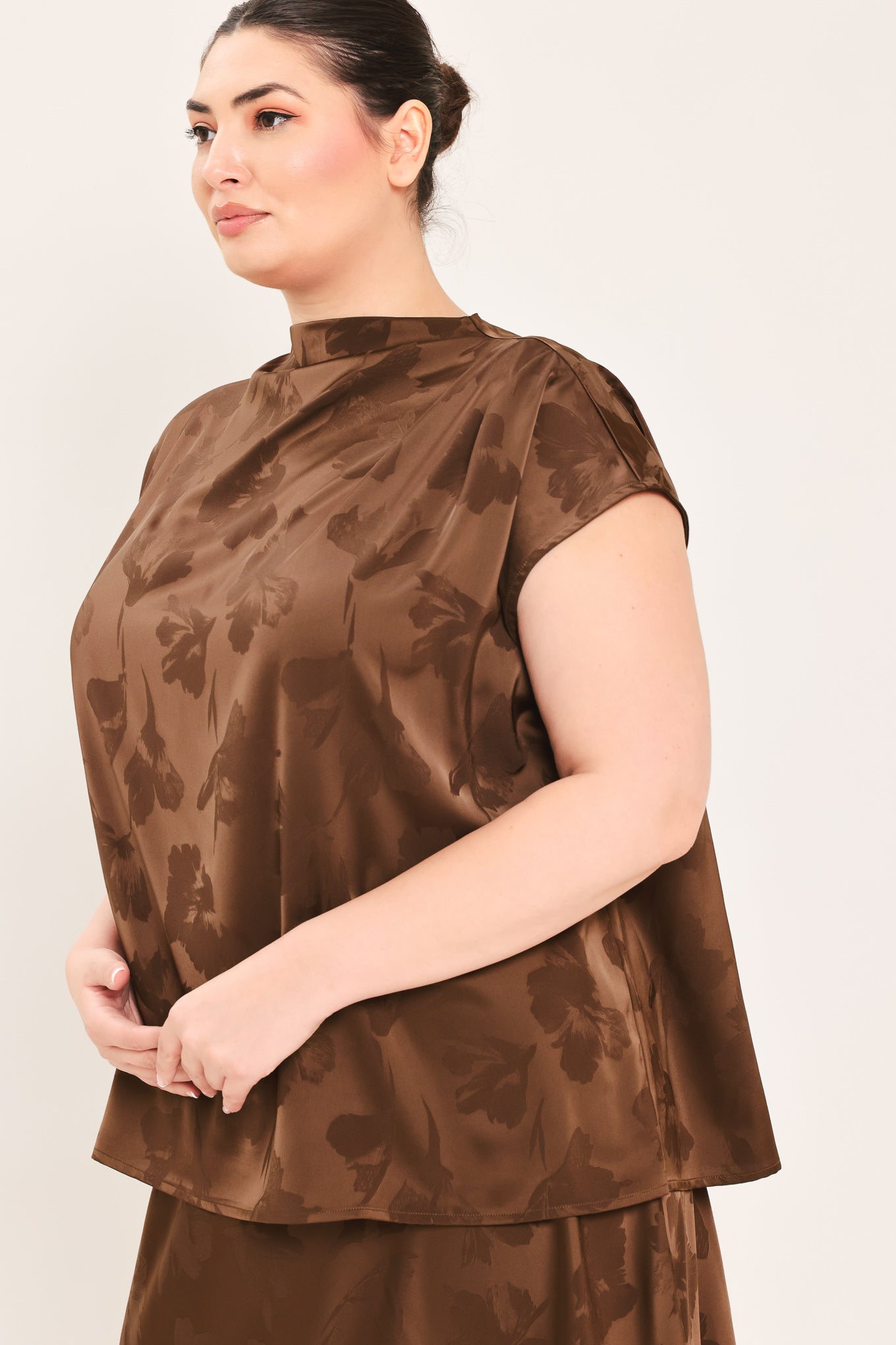 A woman modeling a brown short-sleeve top with a darker brown floral jacquard pattern, paired with a matching brown skirt | Plus Curve Flying Tomato