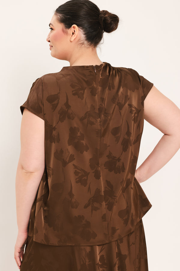 A woman modeling a brown short-sleeve top with a darker brown floral jacquard pattern, paired with a matching brown skirt | Plus Curve Flying Tomato