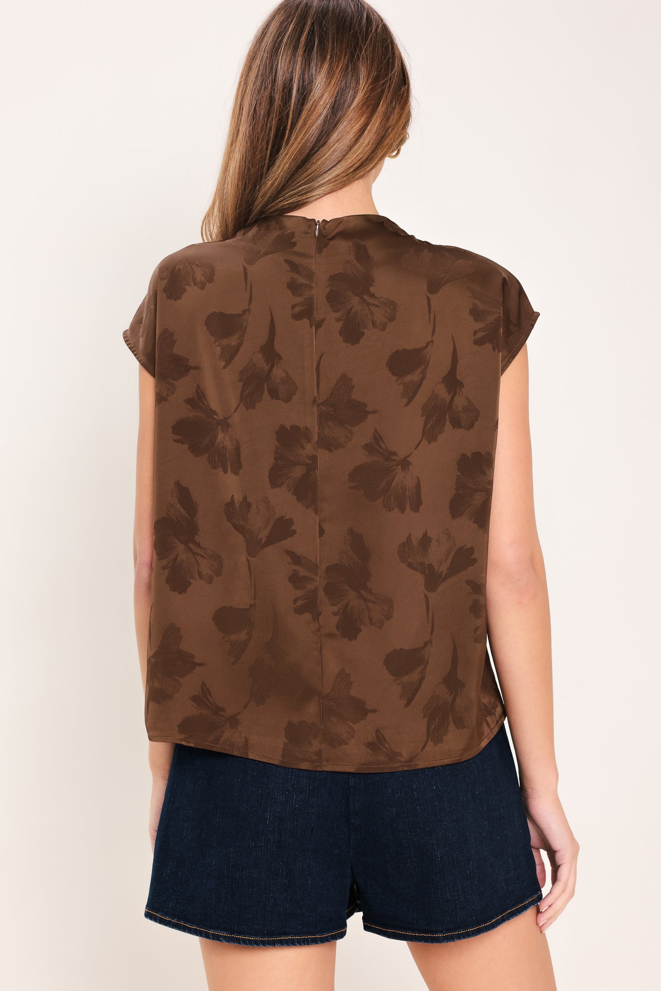 Woman wearing a brown jacquard top featuring funnel neckline, short sleeve and back zipper closure | Flying Tomato