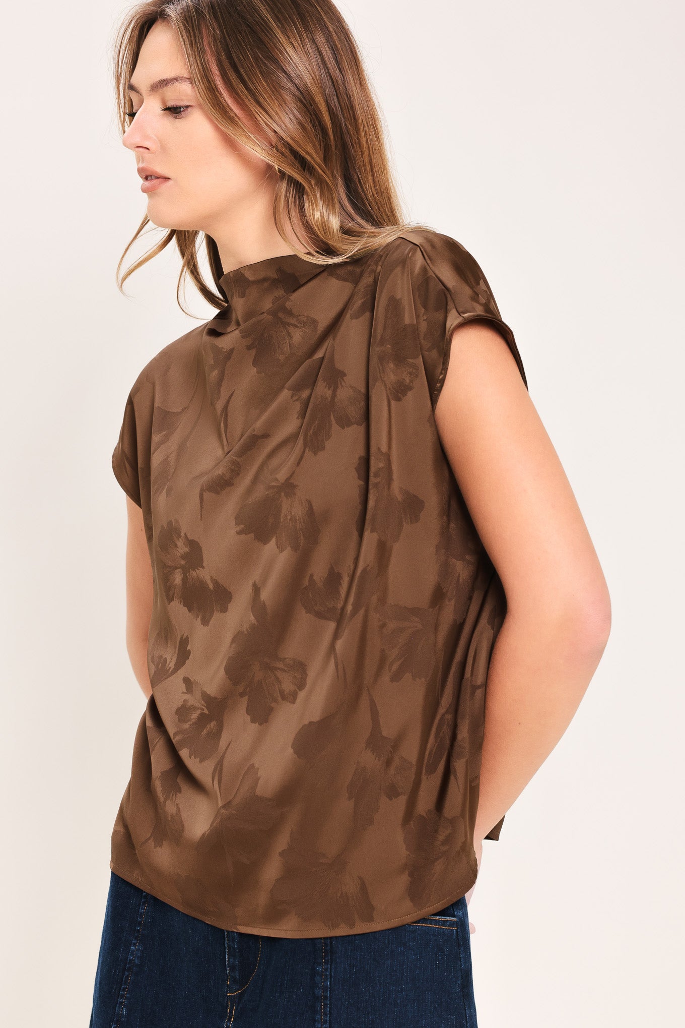 Woman wearing a brown jacquard top featuring funnel neckline, short sleeve and back zipper closure | Flying Tomato