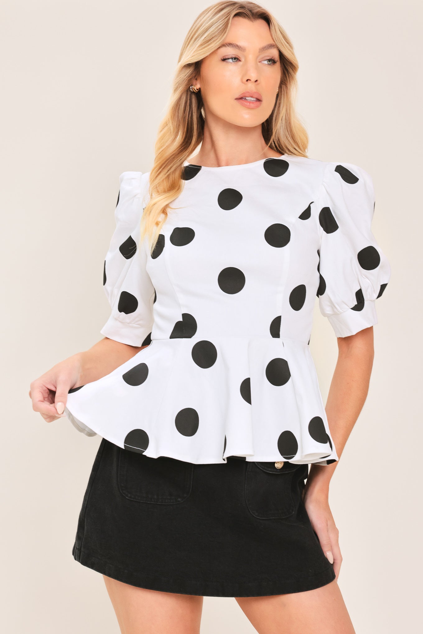 A woman wearing a white short-sleeve blouse with large black polka dots and puffed sleeves | Flying Tomato