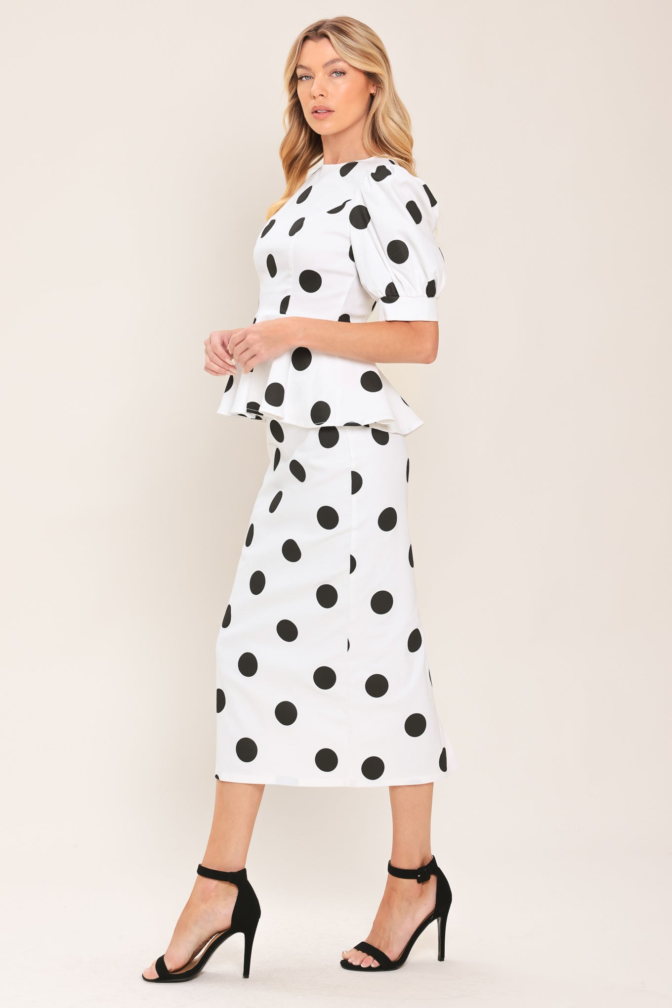 A woman wearing a white short-sleeve blouse with large black polka dots and puffed sleeves | Flying Tomato