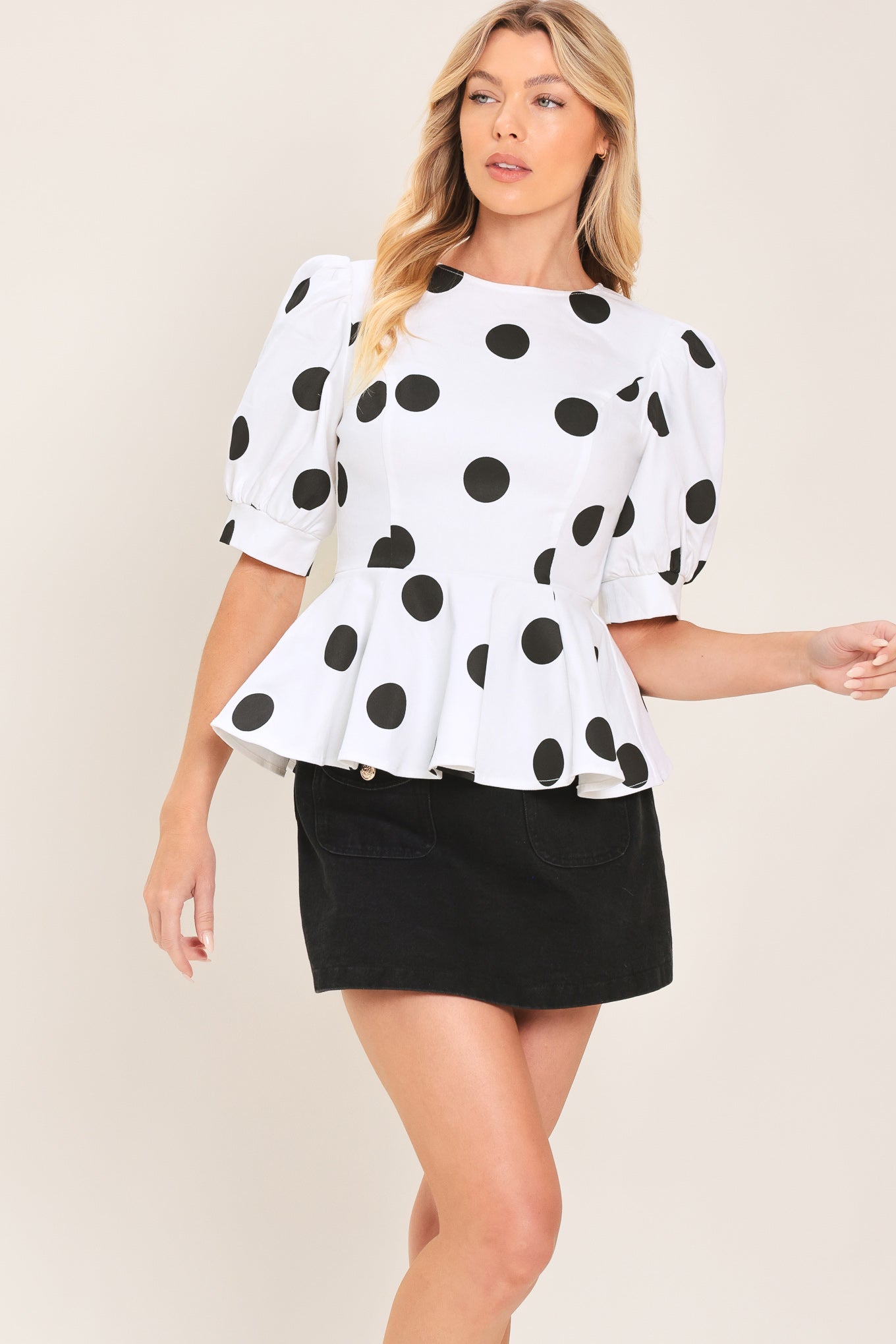 A woman wearing a white short-sleeve blouse with large black polka dots and puffed sleeves | Flying Tomato