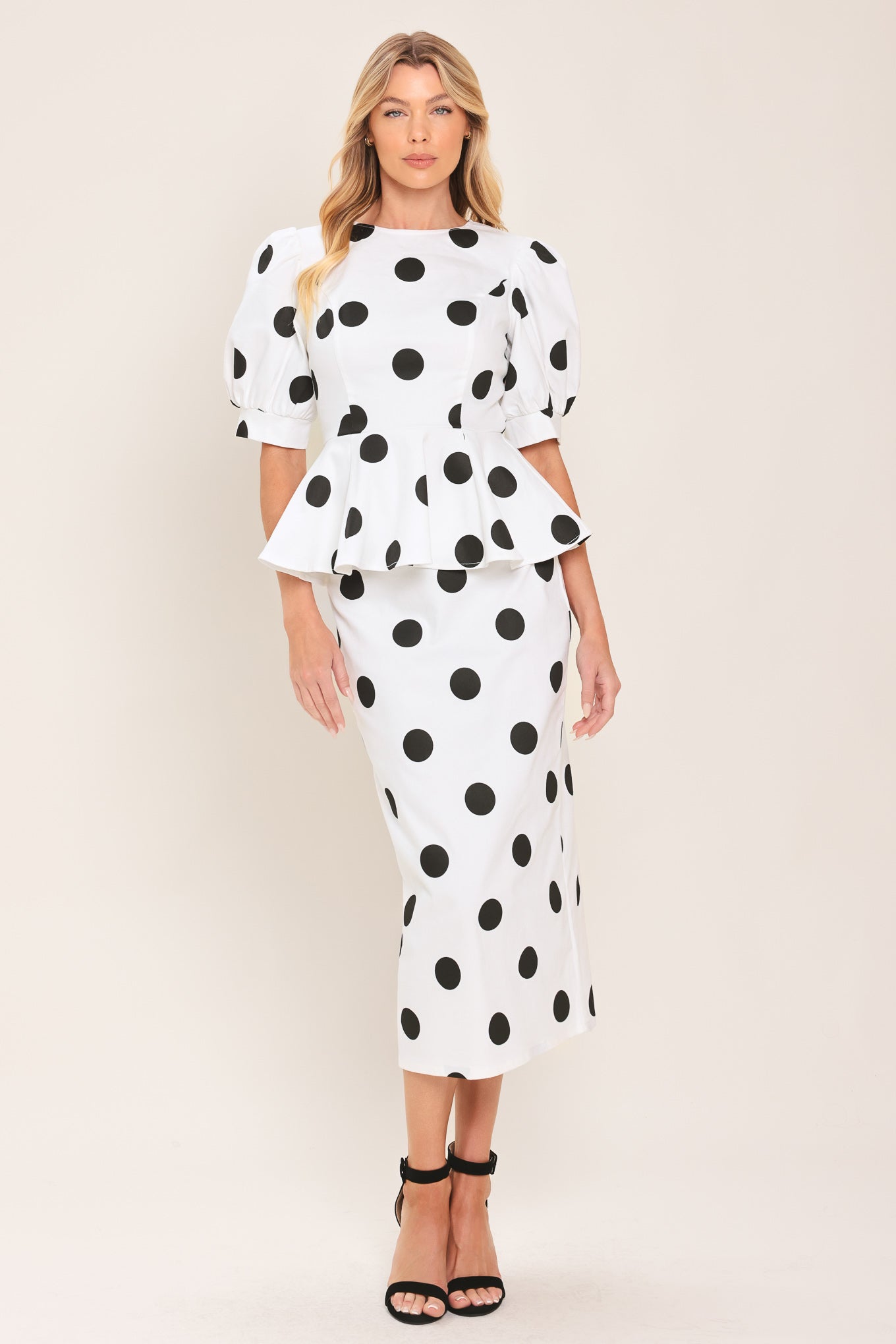 A woman wearing a white short-sleeve blouse with large black polka dots and puffed sleeves | Flying Tomato