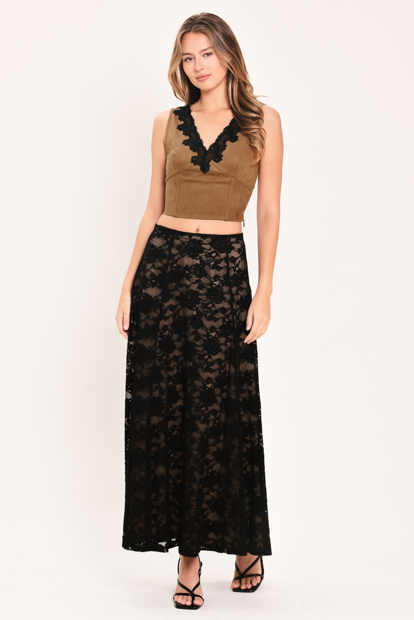A woman wearing a faux suede brown sleeveless crop top with a black lace V-neck trim | Flying Tomato