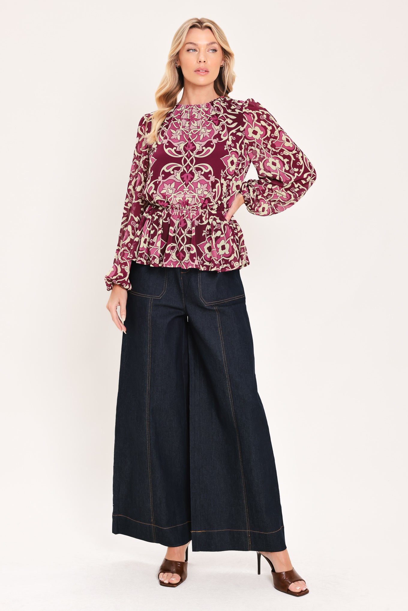 A woman modeling a long-sleeve peplum blouse with a burgundy and beige baroque-style pattern | Flying Tomato