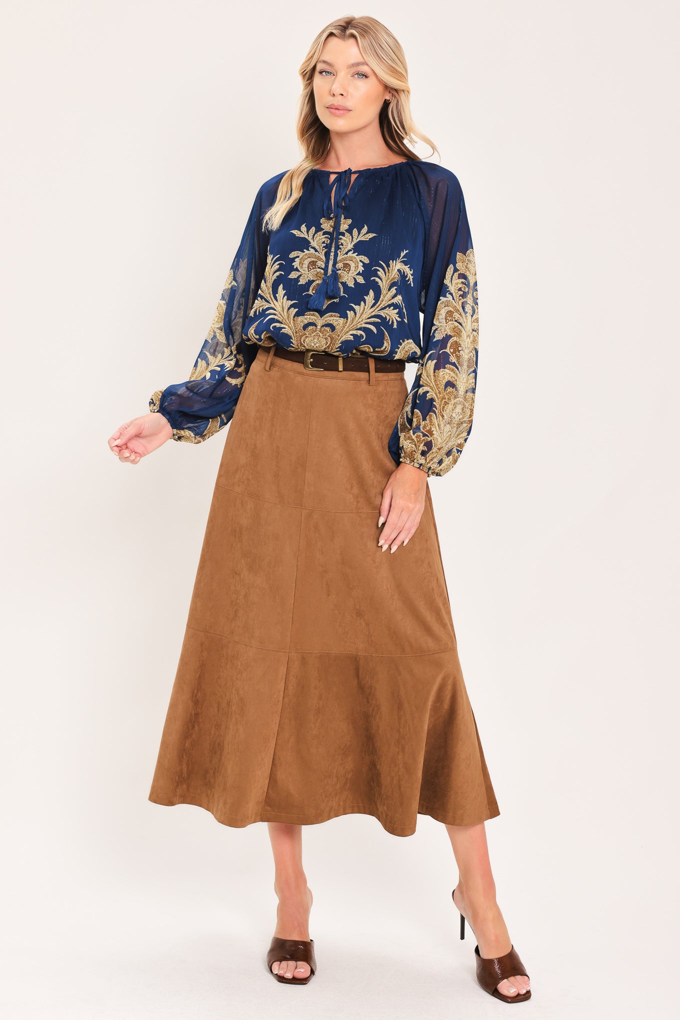 A woman wearing a navy blue long-sleeve blouse with an ornate gold baroque-style pattern and a tie-neck detail | Flying Tomato