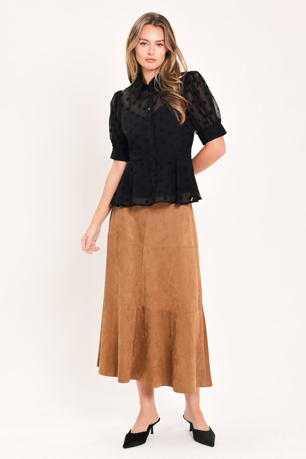 A woman wearing a black sheer puff-sleeve blouse with a subtle polka dot pattern and a peplum waist | Flying Tomato