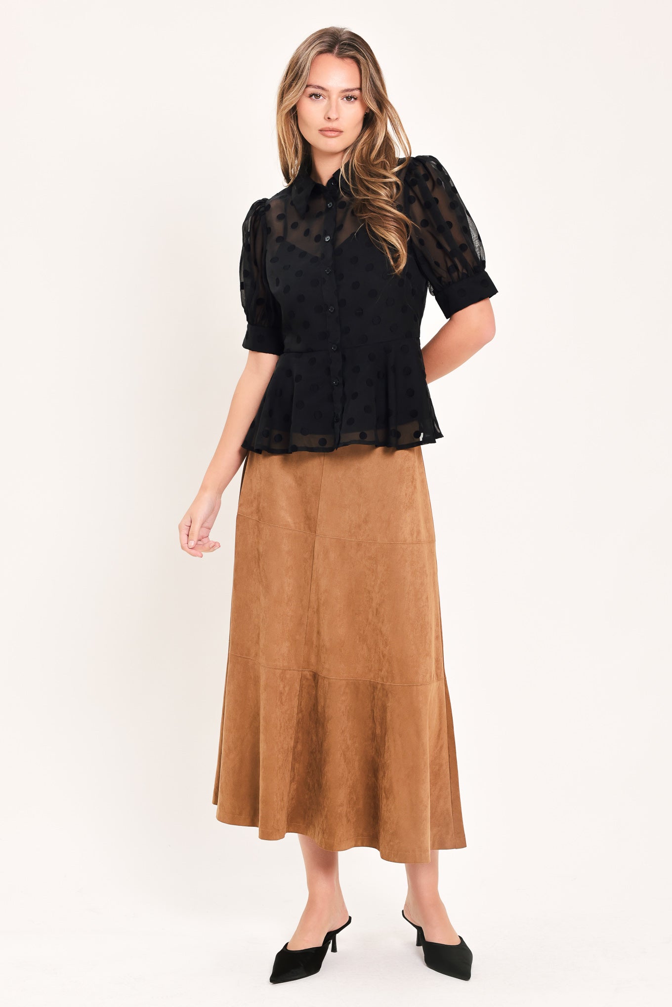 A woman wearing a black sheer puff-sleeve blouse with a subtle polka dot pattern and a peplum waist | Flying Tomato