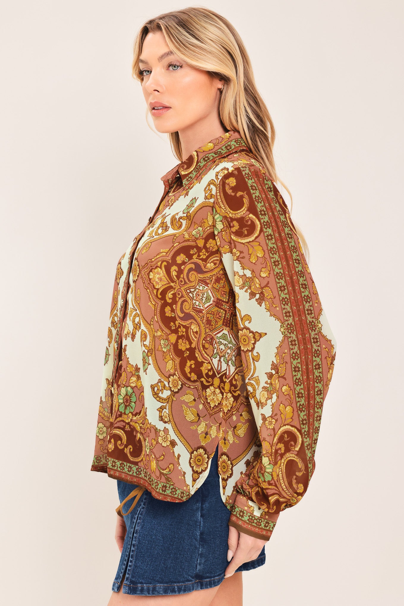 A woman wearing a long-sleeve button-up blouse with an ornate paisley and floral pattern in brown, gold, and cream | Flying Tomato