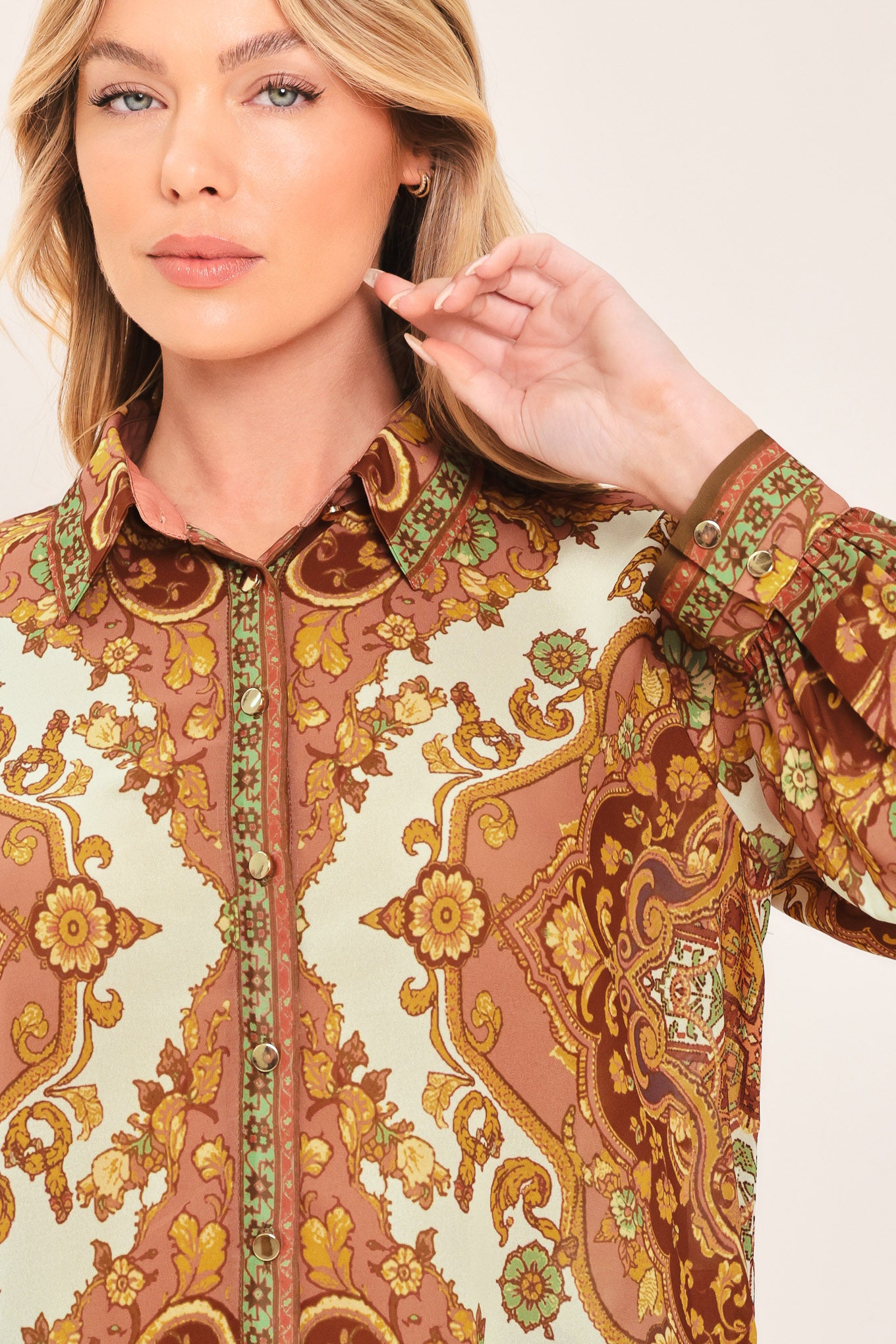 A woman wearing a long-sleeve button-up blouse with an ornate paisley and floral pattern in brown, gold, and cream | Flying Tomato