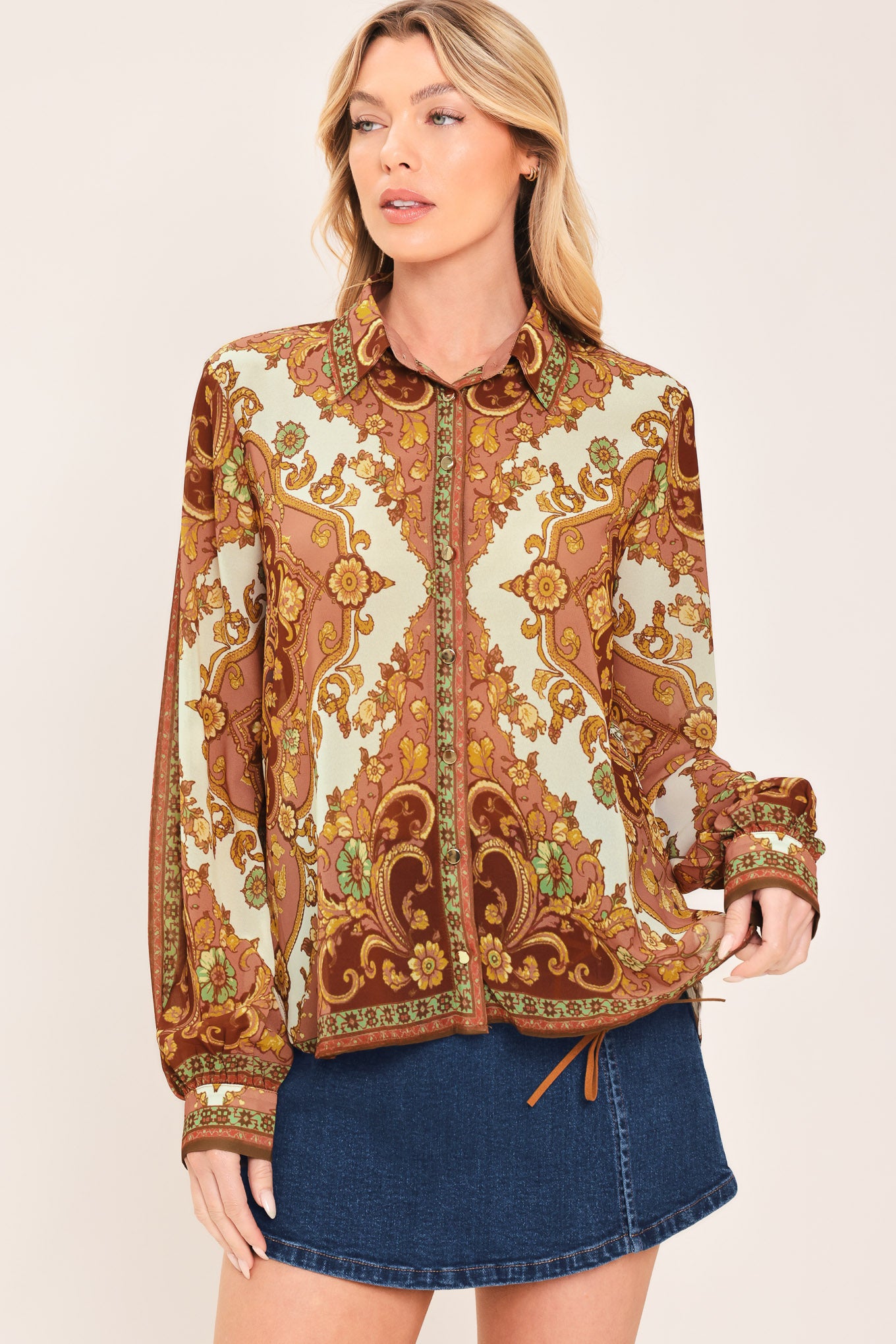 A woman wearing a long-sleeve button-up blouse with an ornate paisley and floral pattern in brown, gold, and cream | Flying Tomato