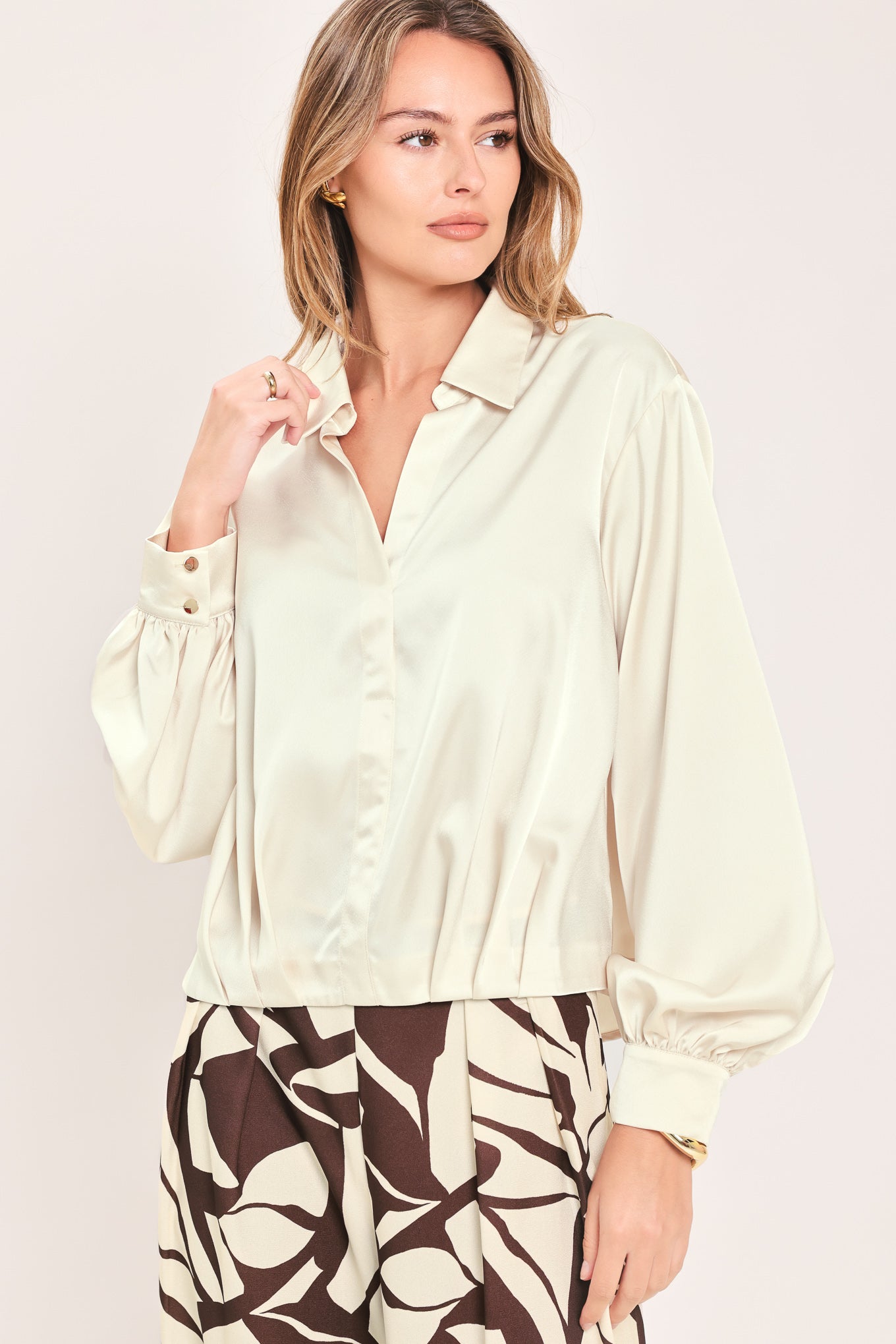 A woman wearing a champagne-colored satin long-sleeve blouse with a button-down front | Flying Tomato