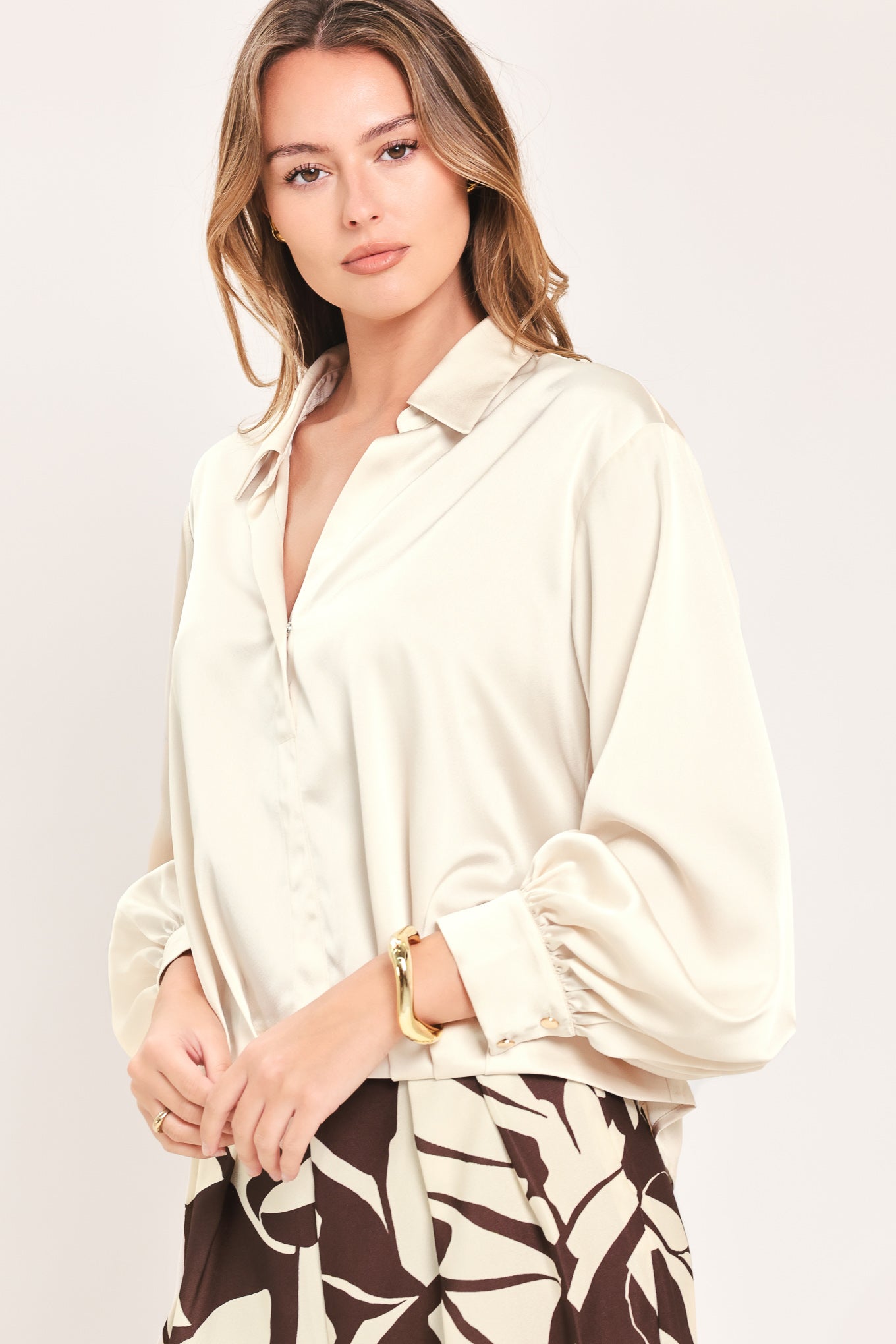 A woman wearing a champagne-colored satin long-sleeve blouse with a button-down front | Flying Tomato