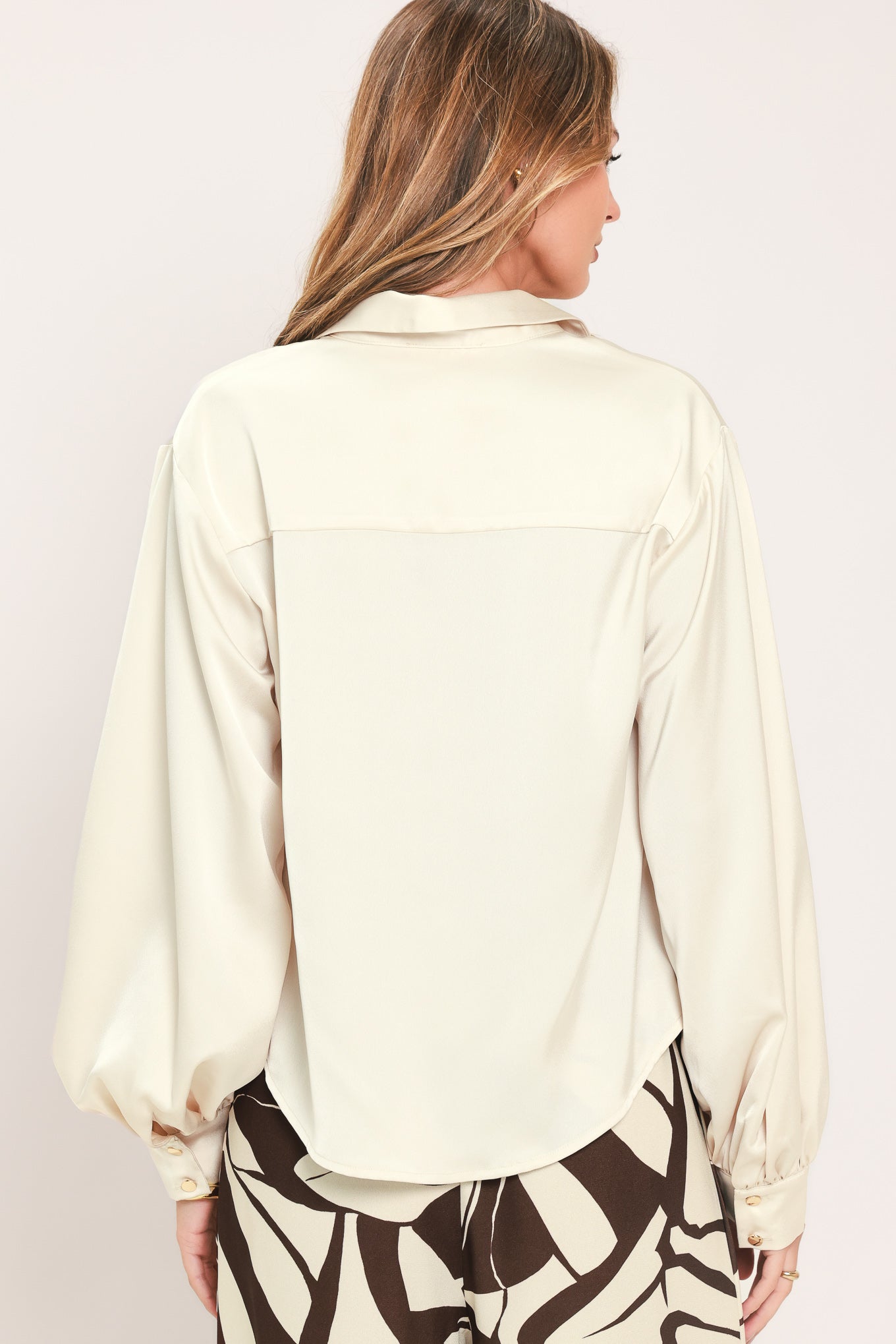 A woman wearing a champagne-colored satin long-sleeve blouse with a button-down front | Flying Tomato