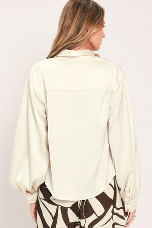 A woman wearing a champagne-colored satin long-sleeve blouse with a button-down front | Flying Tomato