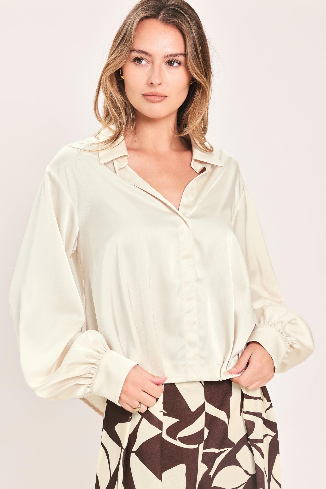 A woman wearing a champagne-colored satin long-sleeve blouse with a button-down front | Flying Tomato